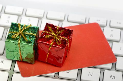 Dovolená koncept online nakupování - miniaturní dárkové krabičky a kreditní nebo dárkové karty na klávesnici počítače.