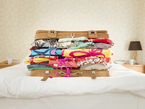Přebalený kufr na posteli, příměstský domov
