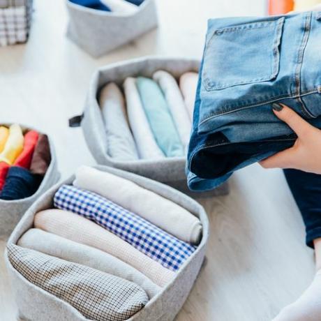 žena skládání oblečení v ložnici, organizování prádla v krabicích a koších koncept minimalistického životního stylu a japonský systém skládání triček metoda konmari