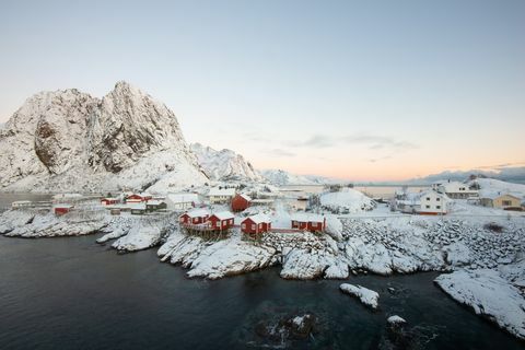 Červený rybářský dům vesnice mezi sněhem s výhledem na hory v Lofoten ostrově Hamnoy Norsko