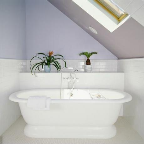 vana pod světlíkem v podkrovní koupelně s fialově fialovými stěnami