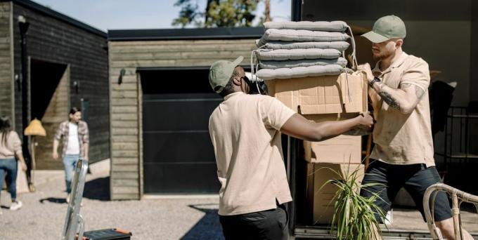doručovatelé vybírají kartonové krabice z náklaďáku během slunečného dne