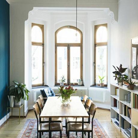 Dřevěný stůl a židle v moderním obývacím pokoji s velkým oknem vpředu ve stylovém bytě