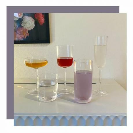 Sortiment různých tvarovaných sklenic na odkládacím stolku s květinovým obrazem visícím na zdi