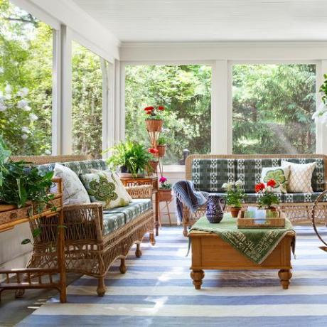 veranda, modrý a bílý pruhovaný koberec, proutěná křesla a pohovka se zelenými a bílými polštáři, pokojové rostliny