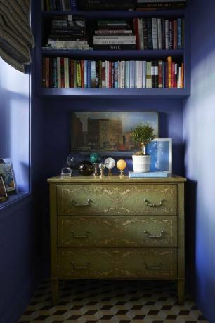 modře malované stěny, zelená komoda, mramorové koule, dekorativní knihy, bílá rostlina v květináči