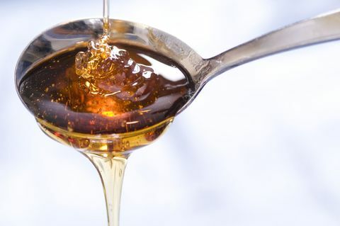 Kapka sirupu nebo medu padá do a z lžíce.