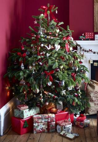 zářivý červený obývací pokoj s tradičním krbem a krbem, zapálený oheň, dřevěná podlaha, zabalené dárky pod ozdobeným vánočním stromem v rohu místnosti, dekorace, girlanda, klasický,