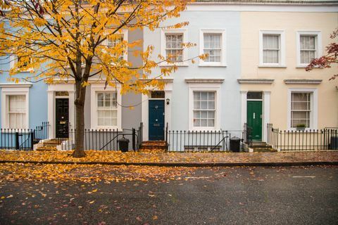 Notting Hill sousední domy s pastelovou barevnou fasádou s pěknou kompozicí bez aut a stromem s podzimní listí na zemi v Londýně. Velká Británie, Evropa.