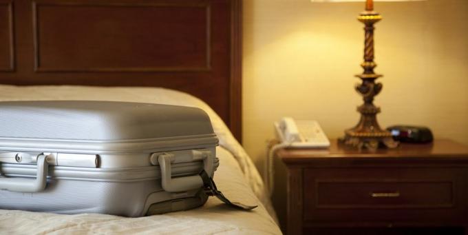 kufr na posteli v hotelovém pokoji