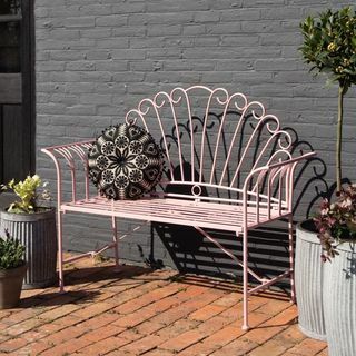 Krásná růžová kovová zahradní lavička
