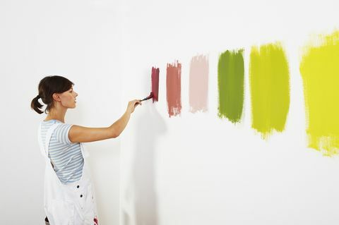 Žena malování barevné vzorníky na zdi