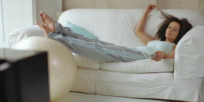 žena ležící na pohovce pomocí dálkového ovládání televize